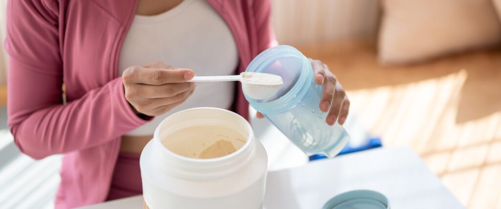 A woman putting powder in a drink after exercising